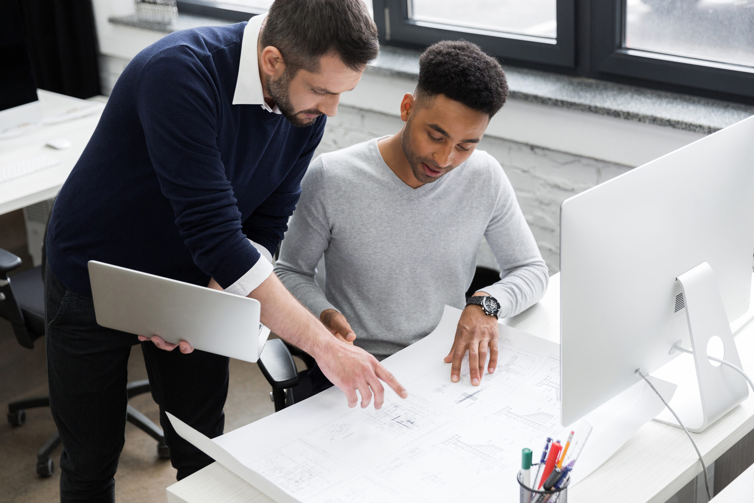 Two young smiling male workers working on a new business project at the office